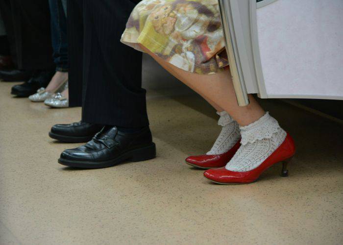 A women in red heels wearing frilly white socks. She is sitting on a train.